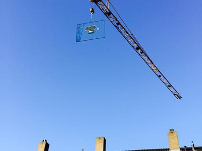 Grote isolatieruit met behulp van een torenkraan over de woning gehesen.